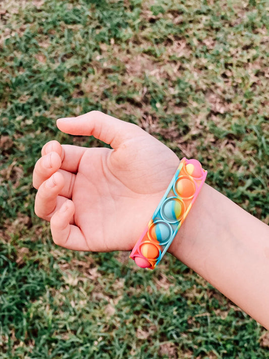 Pop It Bracelet Band - Fidget Toy This wearable Pop It Wristband is great for stress relief, fun and easy to use. We have these in a marble rainbow colour of blues, hot pinks yellows and orange.